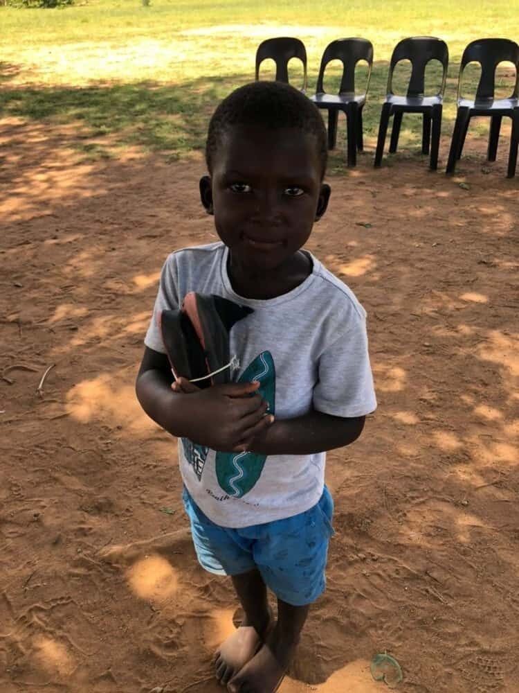 Child at Dakamela Primary School carrying his new shoes